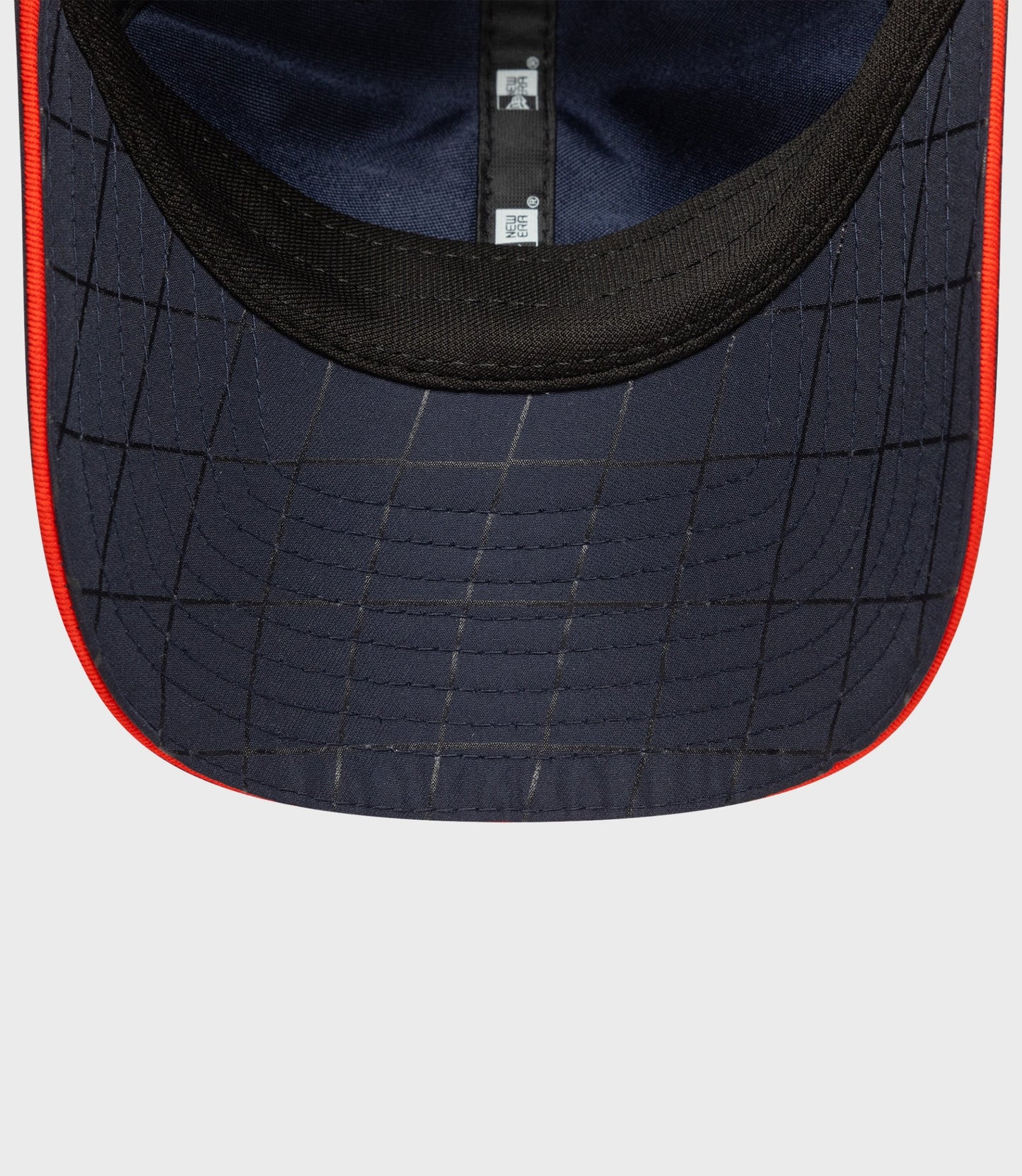 Close up of navy cap brim with red edge piping and grid stitching and inner label visible
