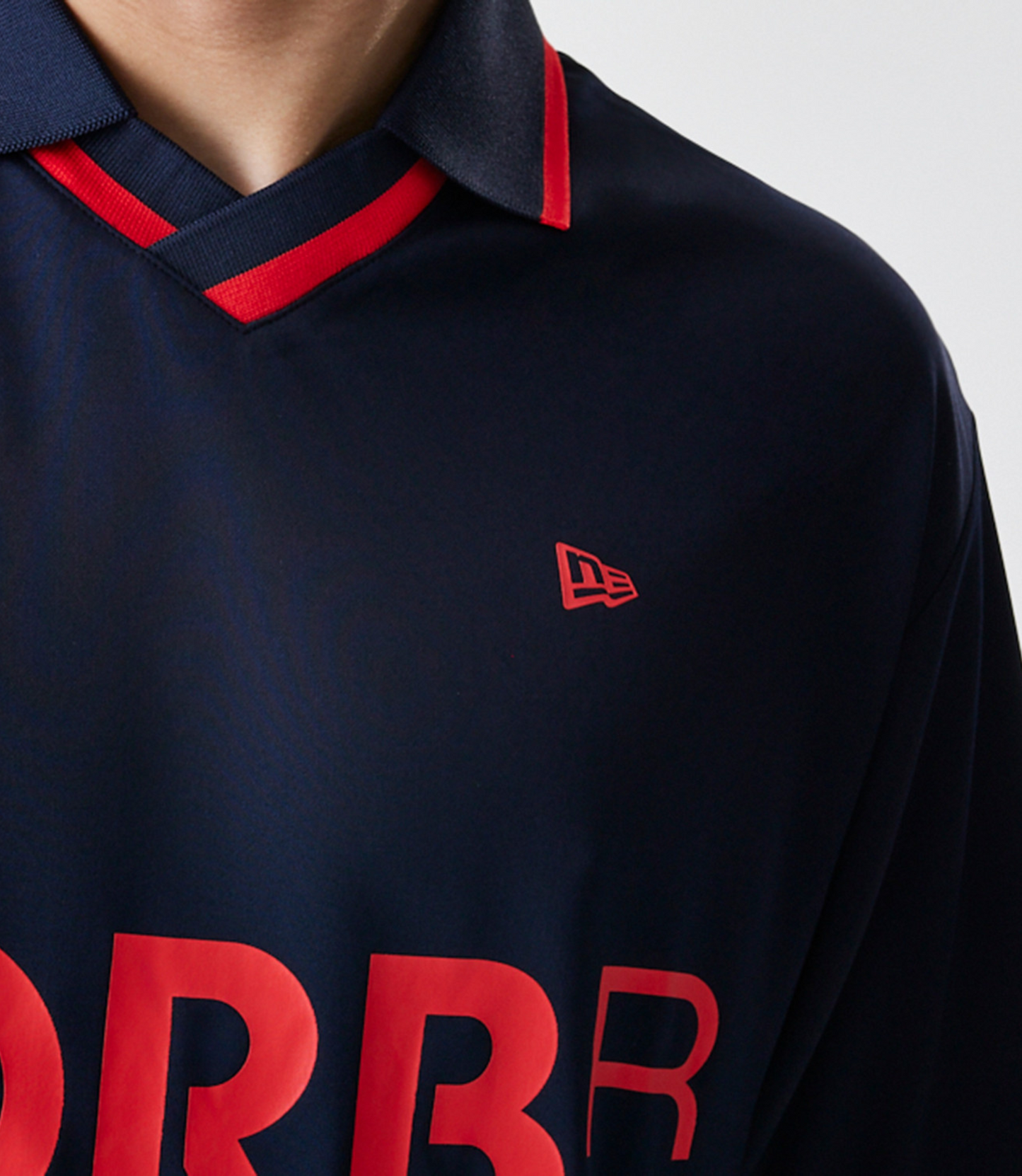 Close up of navy shirt with bold red ORBR letters across front and small New Era flag logo.