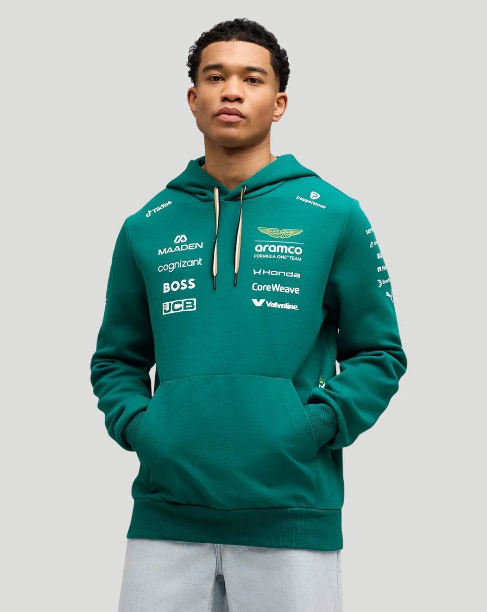 Male model wearing a green Aston Martin F1 team hoodie with front sponsor logos.