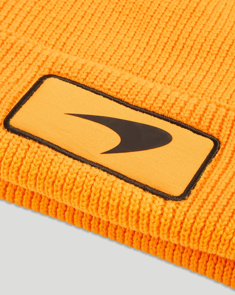 Close up of the orange beanie cuff showing a rectangular patch with a black Puma logo
