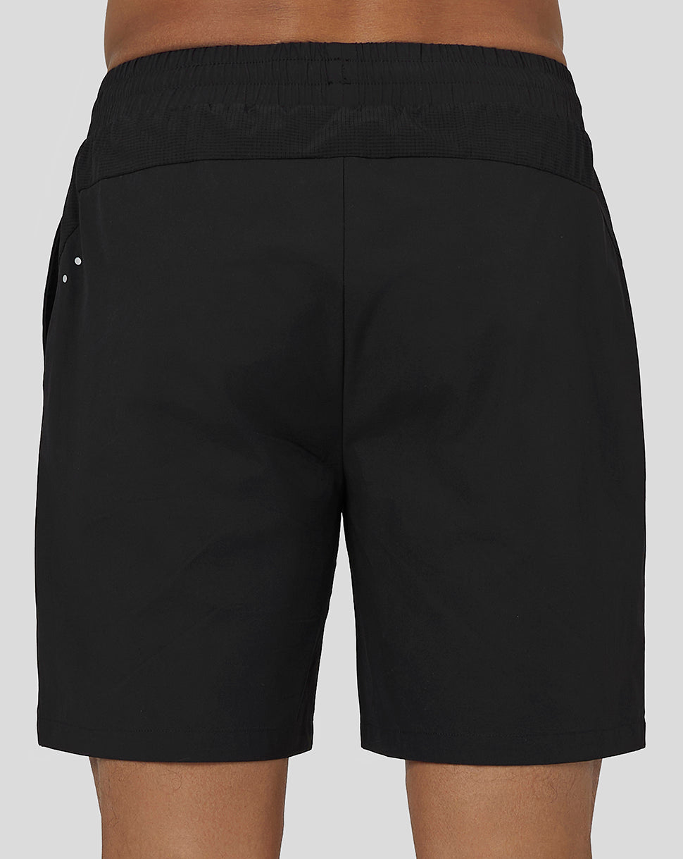 Back view of black men's active woven shorts with elastic waistband and three reflective dots at the left hip