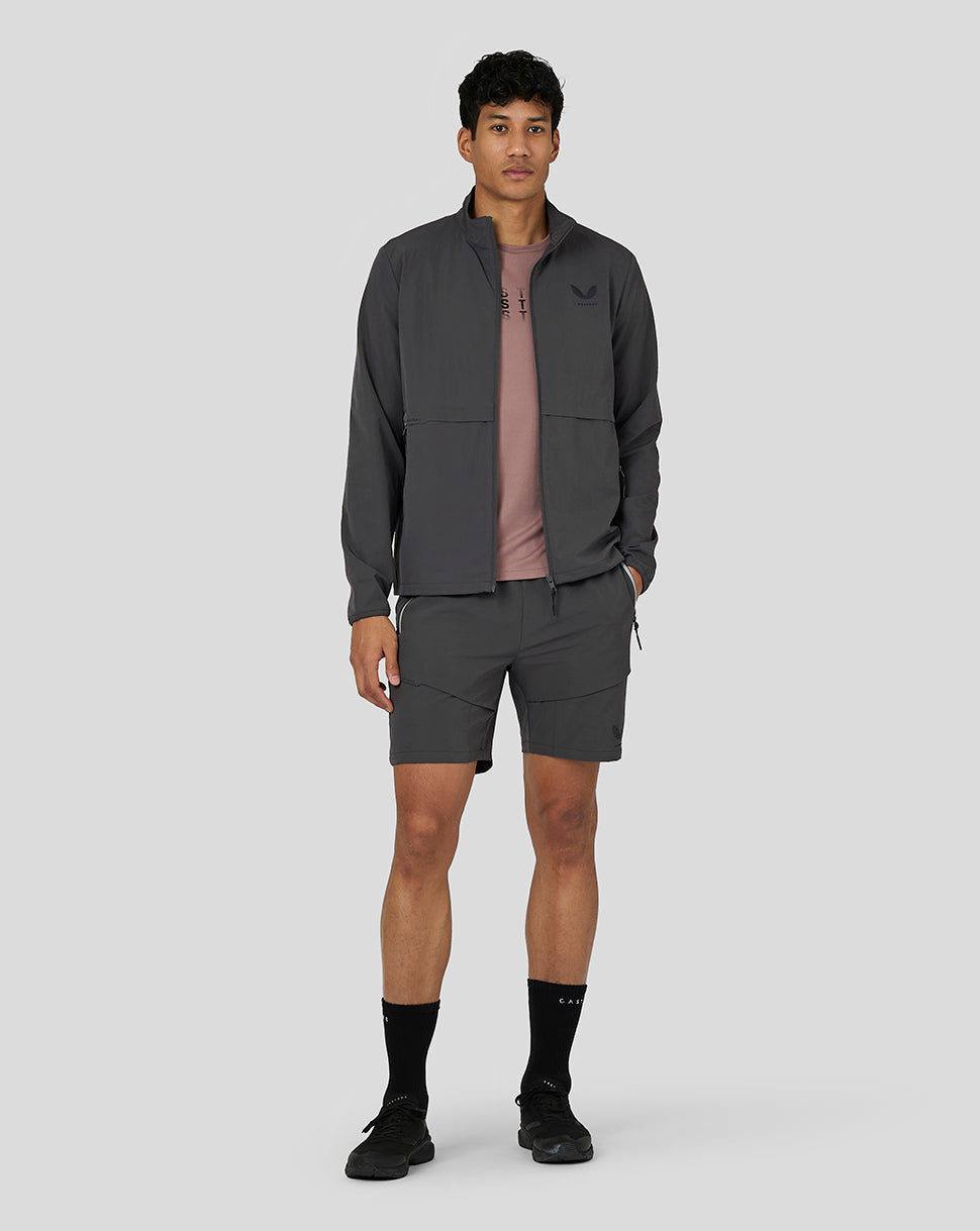 Male model wearing a dark gray zip jacket with matching cargo shorts from Castore Flex collection