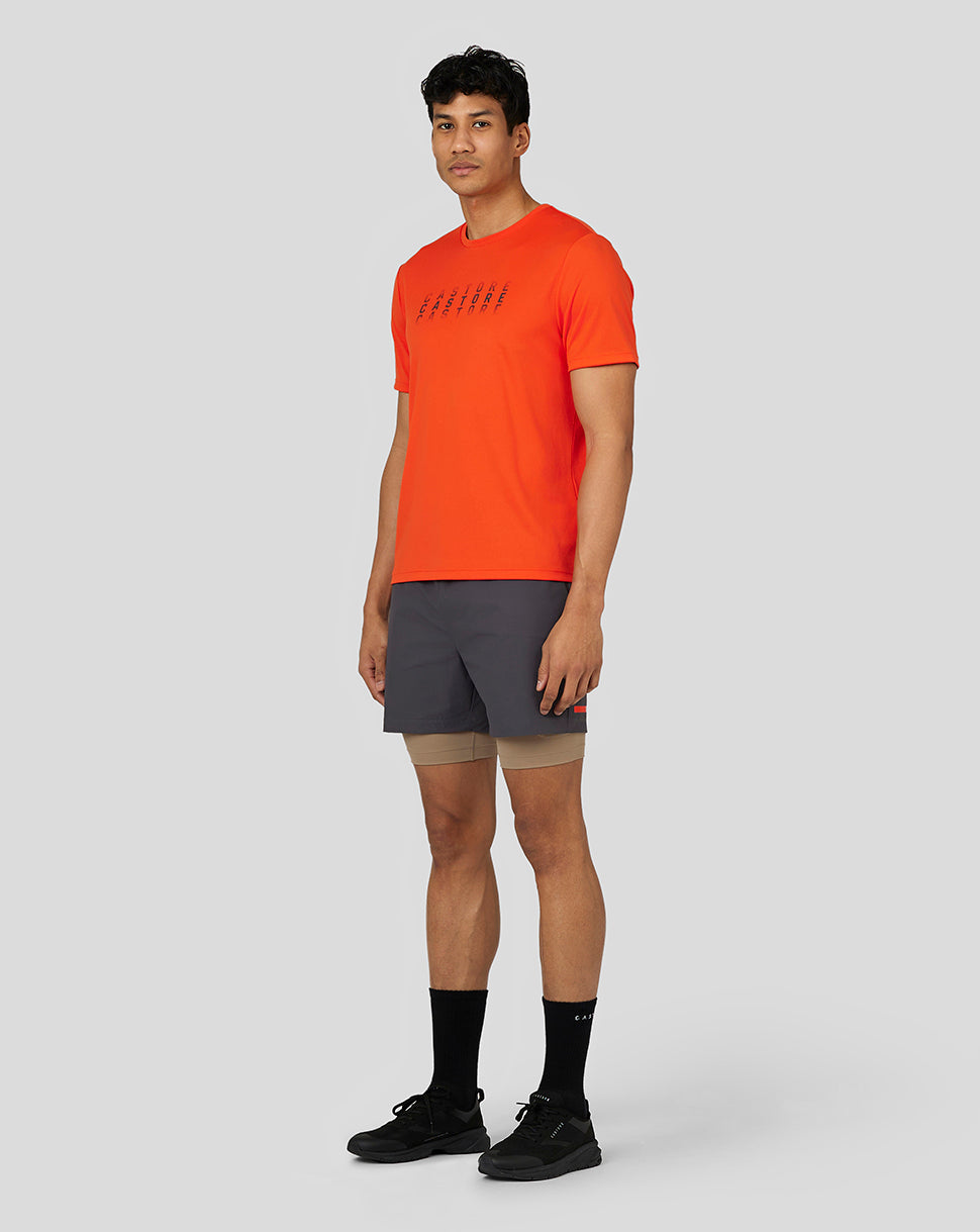 Male model wearing bright orange Flow Short Sleeve Graphic T Shirt with chest Castore graphic