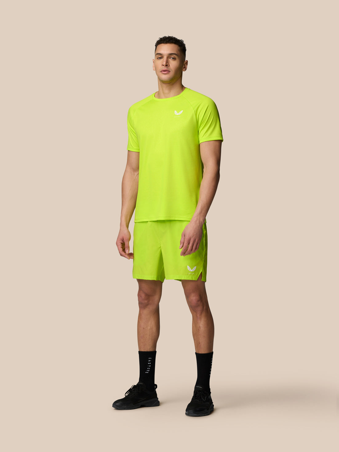 Male model wearing neon lime Adapt Training T-shirt with matching shorts in a full body shot.
