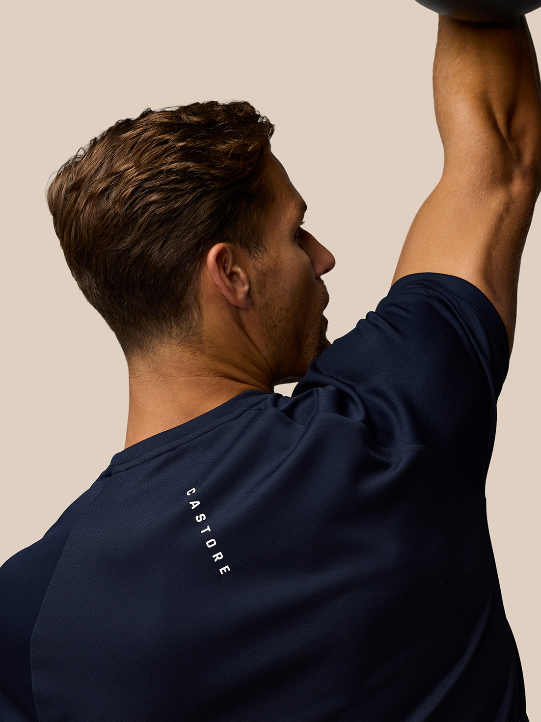 Back view of a male model in the midnight navy Adapt Training T-Shirt with Castore branding along the upper back.