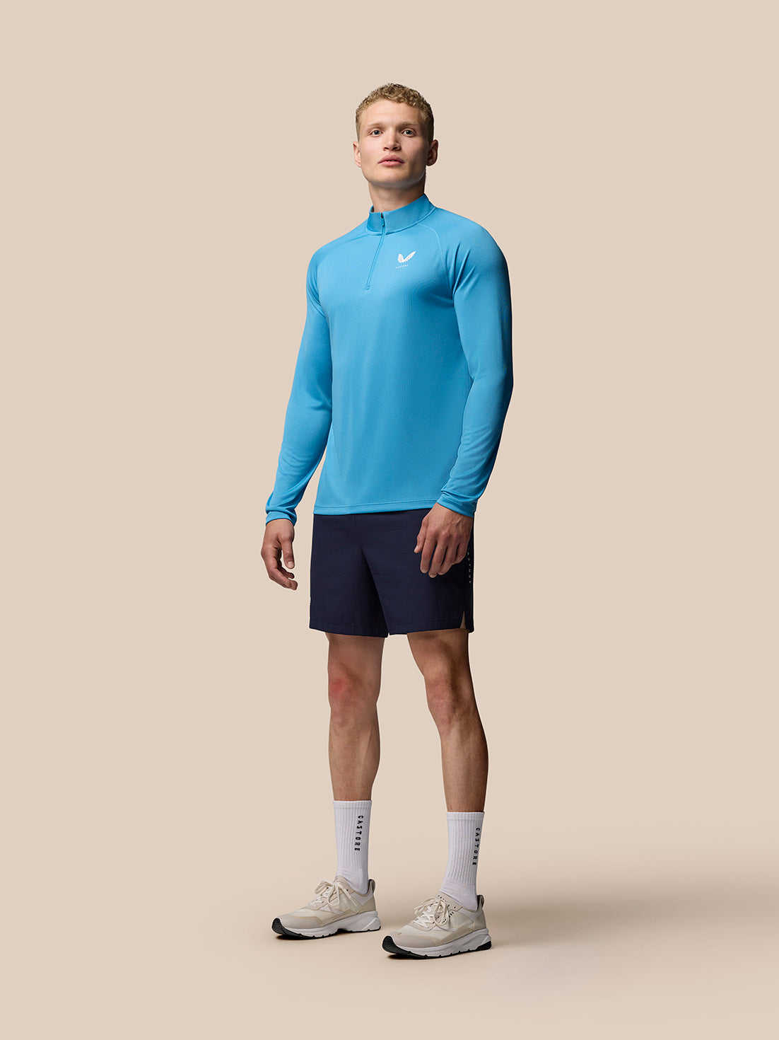 Full body shot of a man wearing corn blue Adapt Training 1/4 Zip Top with stand collar and raglan long sleeves.