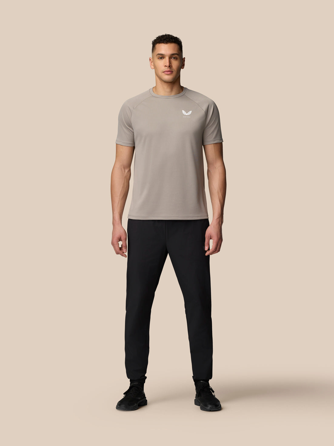 Full-body shot of a male model wearing black Adapt Training Joggers with a light brown top.
