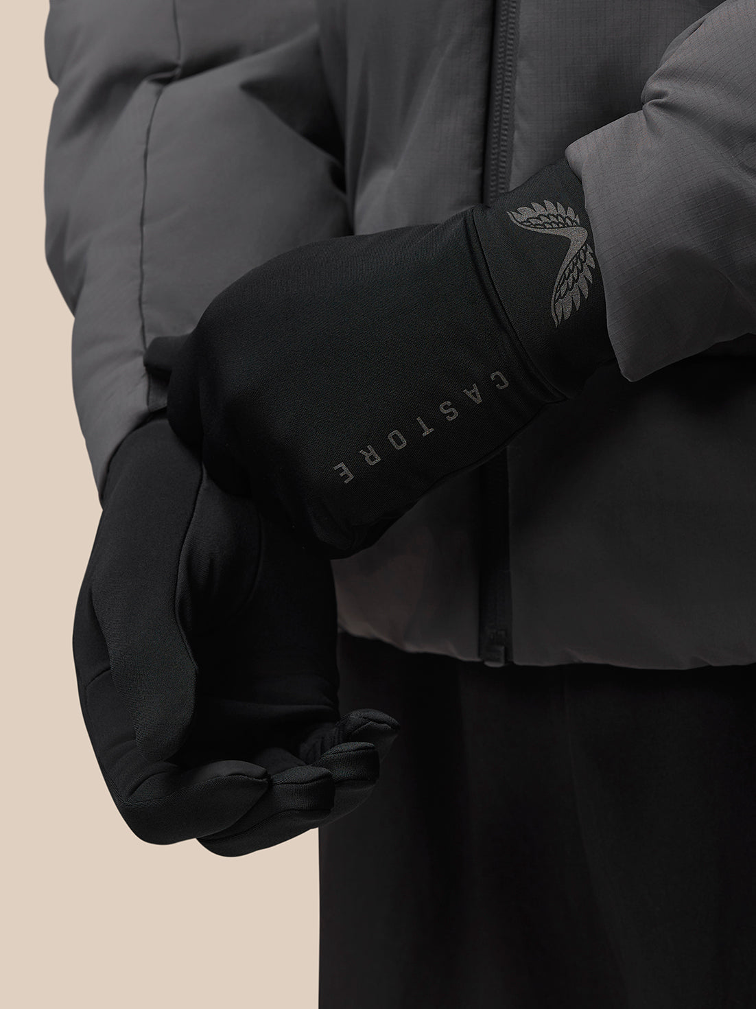 Close up of a black Castore glove featuring a reflective wing emblem and brand lettering along the cuff