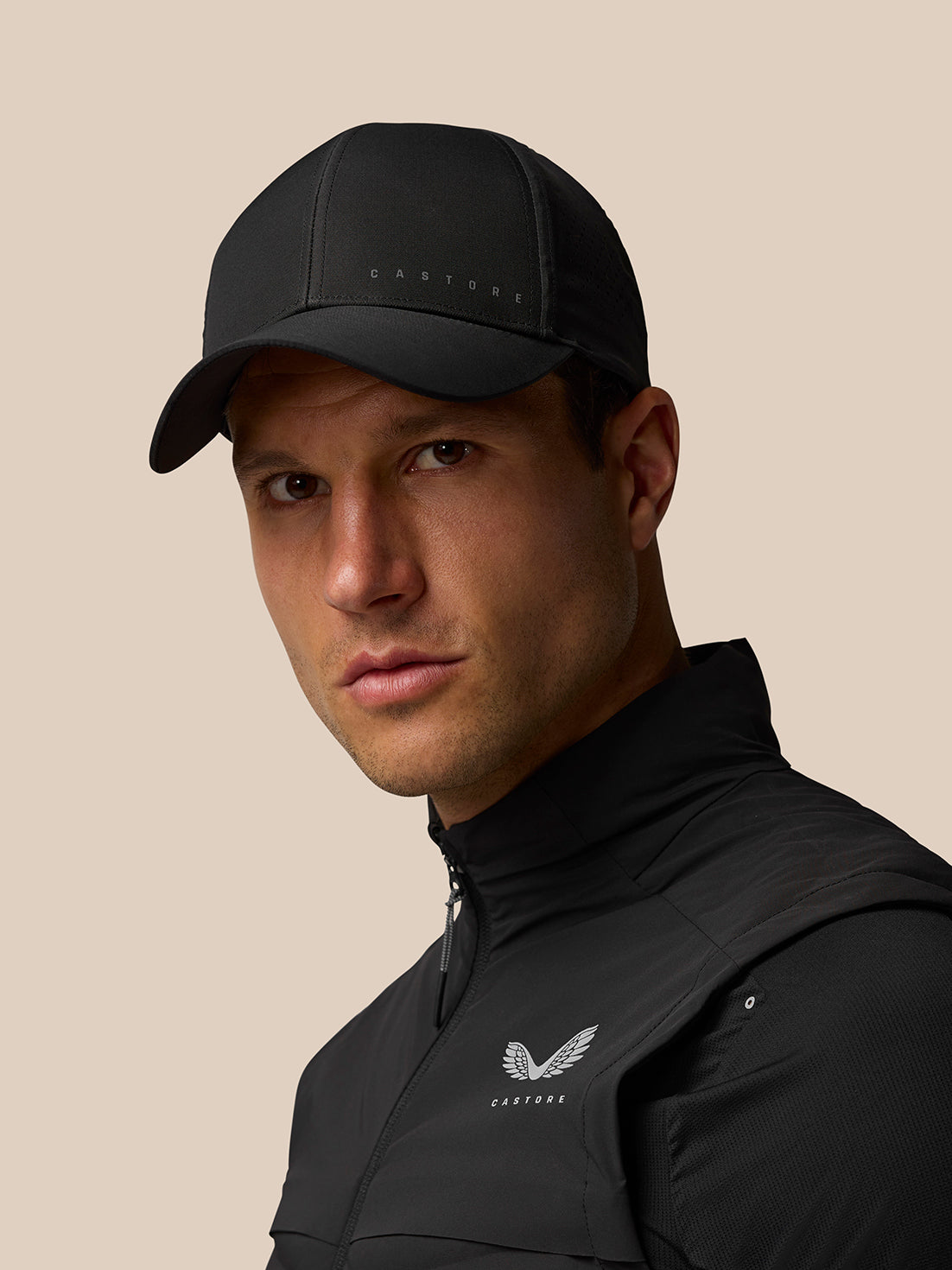 Model wearing black Zone Ventilation Cap with back fastener and Castore branding.