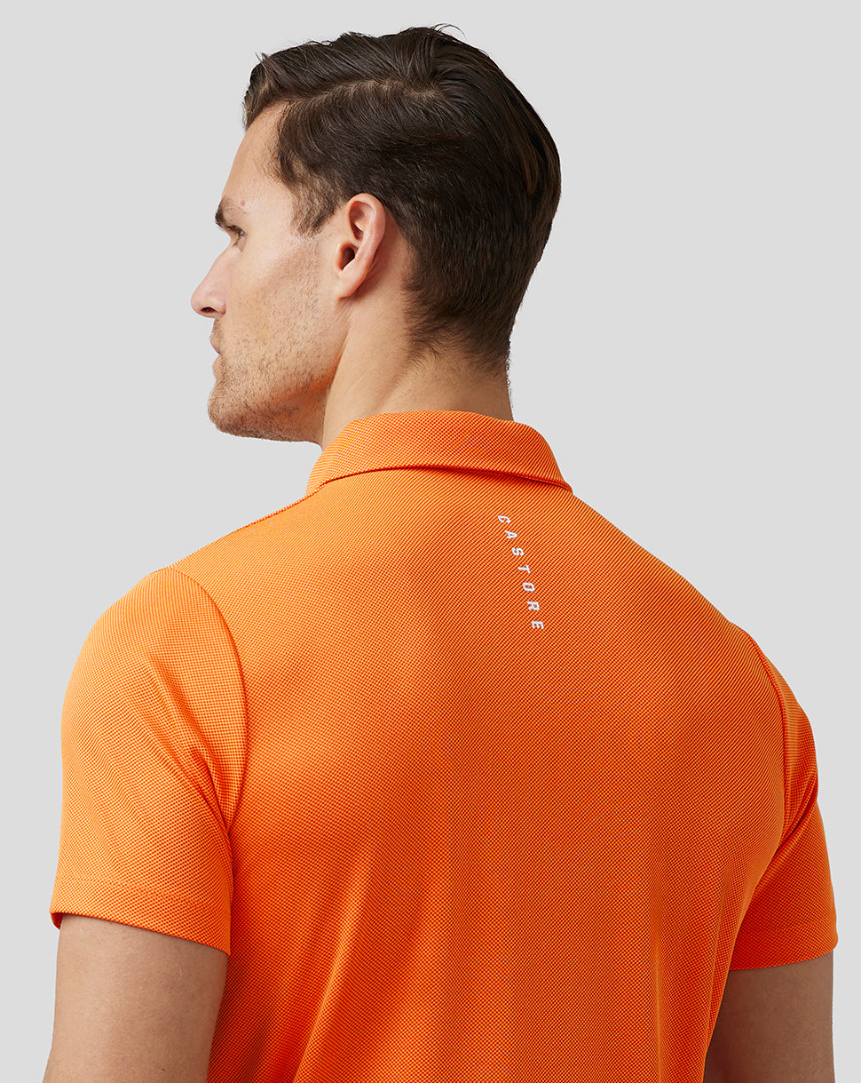 Back view of a male model wearing bright orange textured golf polo with Castore branding on upper back