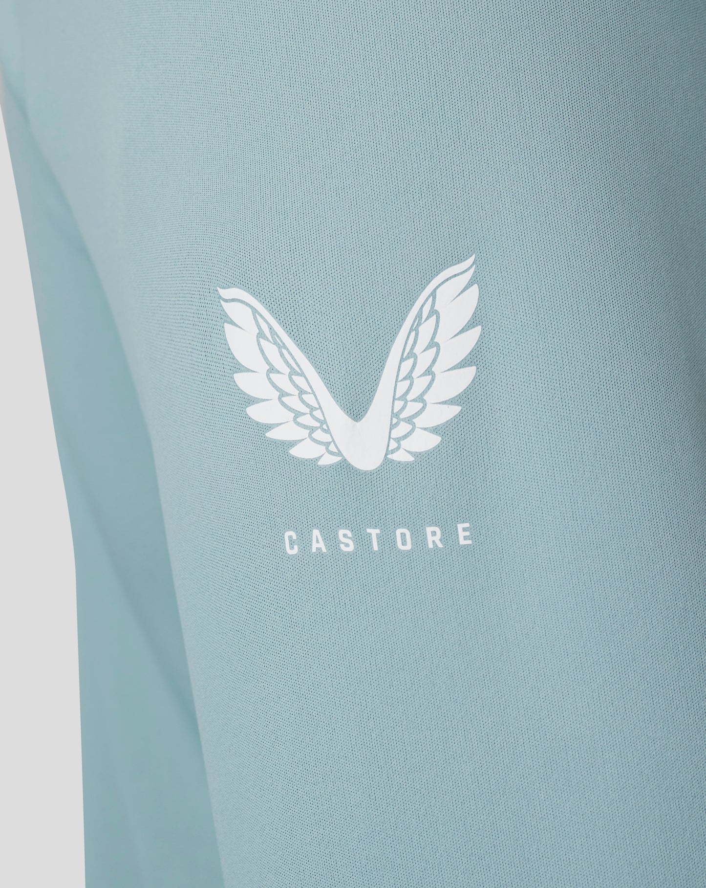 Close-up of stone blue fabric from the Classic 1/4 Zip showing a white Castore wing logo.