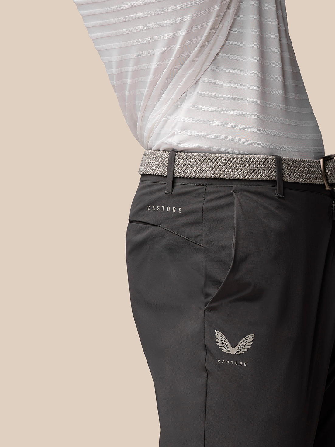 Close up of charcoal Golf Joggers at the waist with a woven belt, Castore branding on the right thigh and Protek branding on the left rear