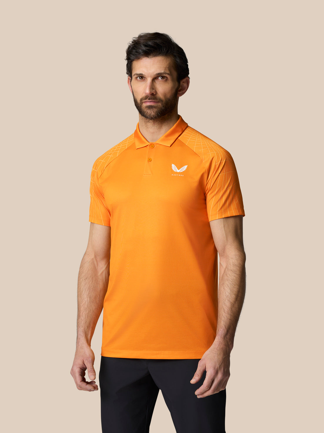 Male model wearing Mango orange Club Graphic Polo with white crest on the chest and subtle shoulder pattern.