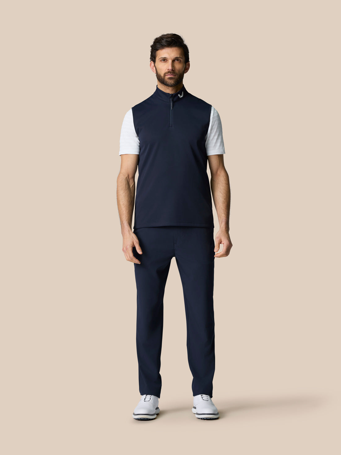 Full body front view of male model in navy Club Classic 1/2 Zip Gilet with navy pants and white golf shoes