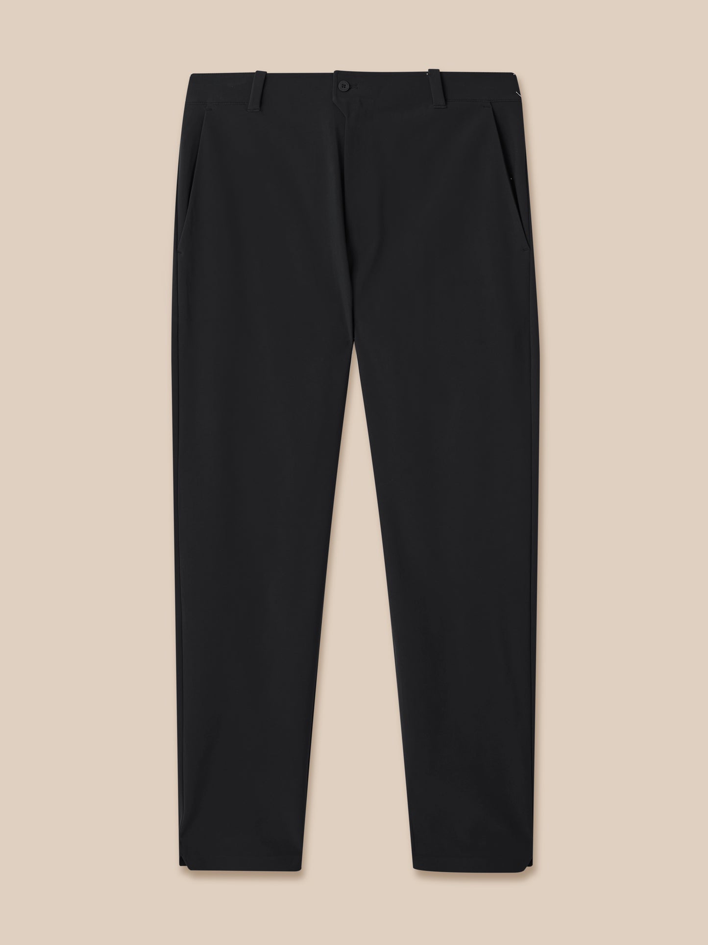 Close up of black golf trousers with belt loops and front pockets against a tan background
