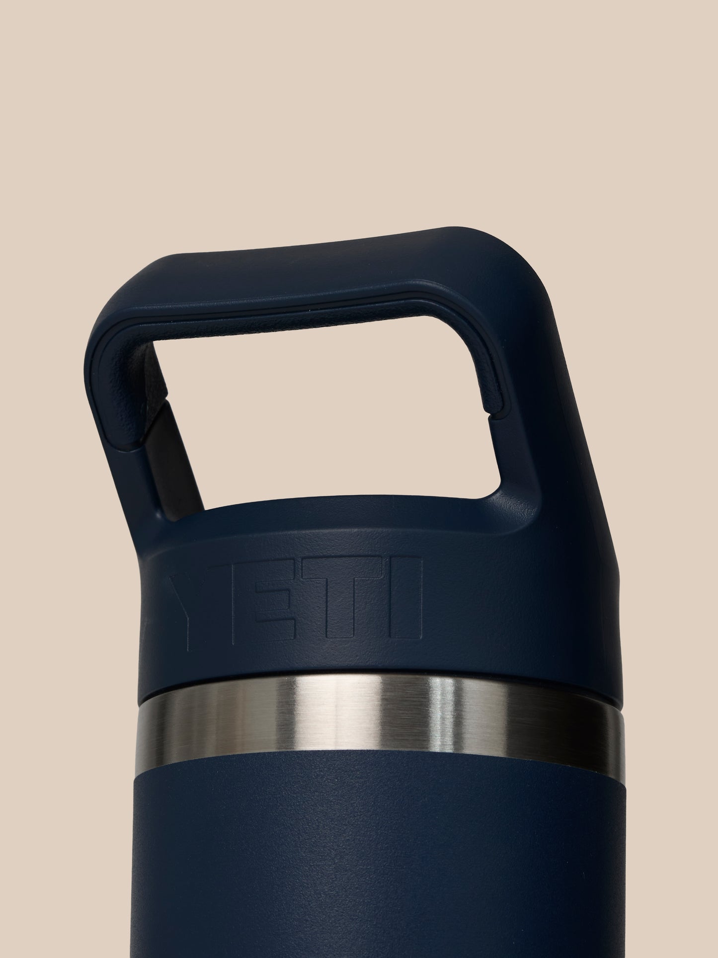 Neck area of YETI Rambler 532 ml showing stainless steel band and embossed YETI logo on dark blue bottle