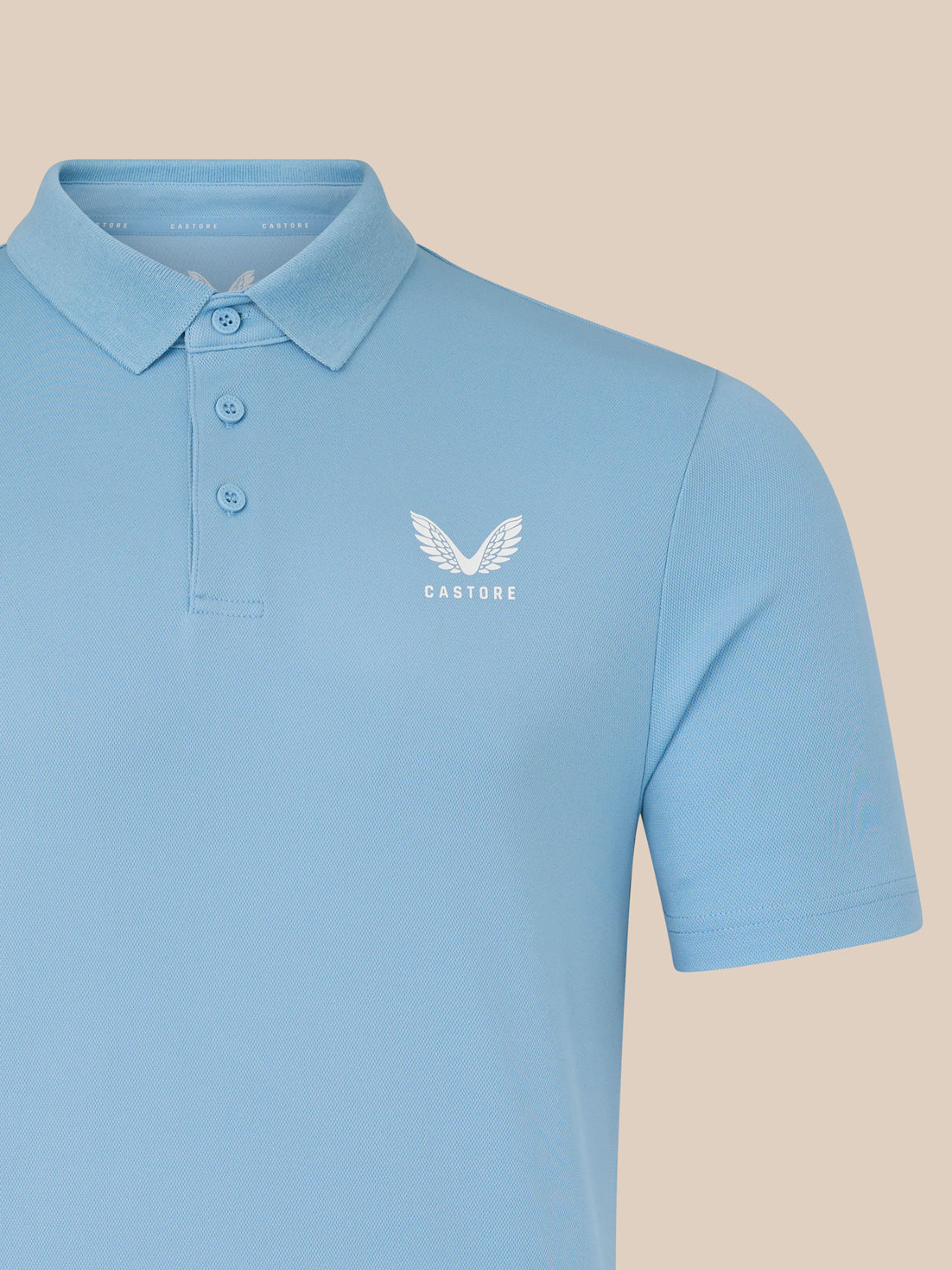 Close-up of the chest area on a light blue men's Core Golf Polo showing the white CASTORE logo