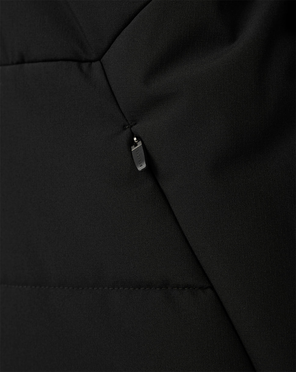 Close-up of a black quilted puffer jacket showing a diagonal seam and a small silver zipper pull.
