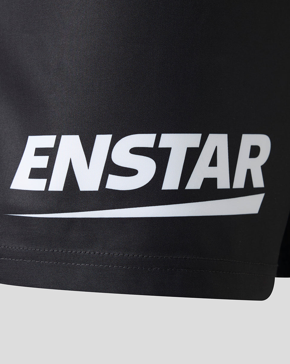 Close-up of a black athletic garment, likely shorts, featuring a large white ENSTAR logo printed across the front.