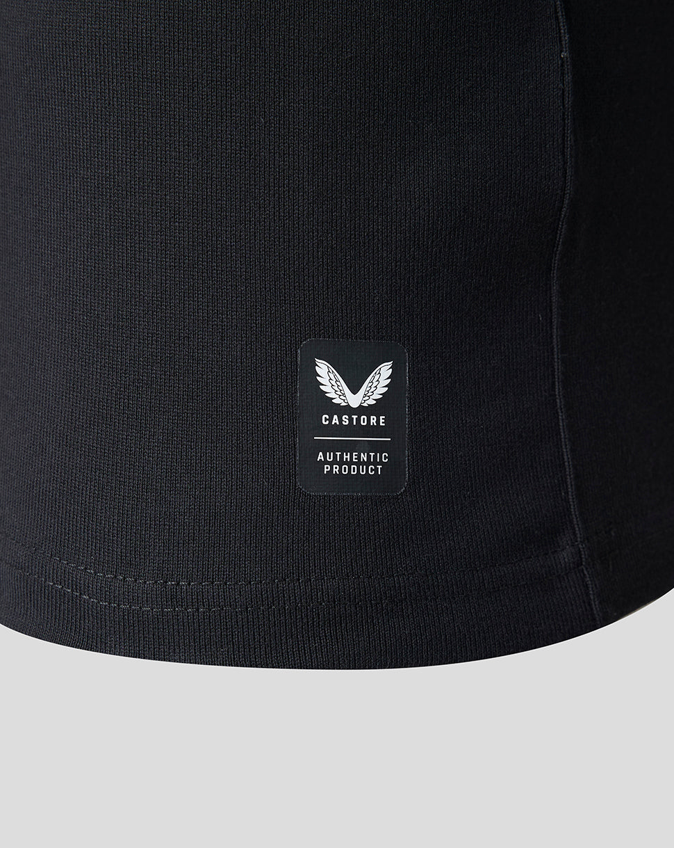 Close-up of a black ribbed knit garment, likely a sweatshirt or jacket, showing a small rectangular Castore Authentic Product patch on the front.