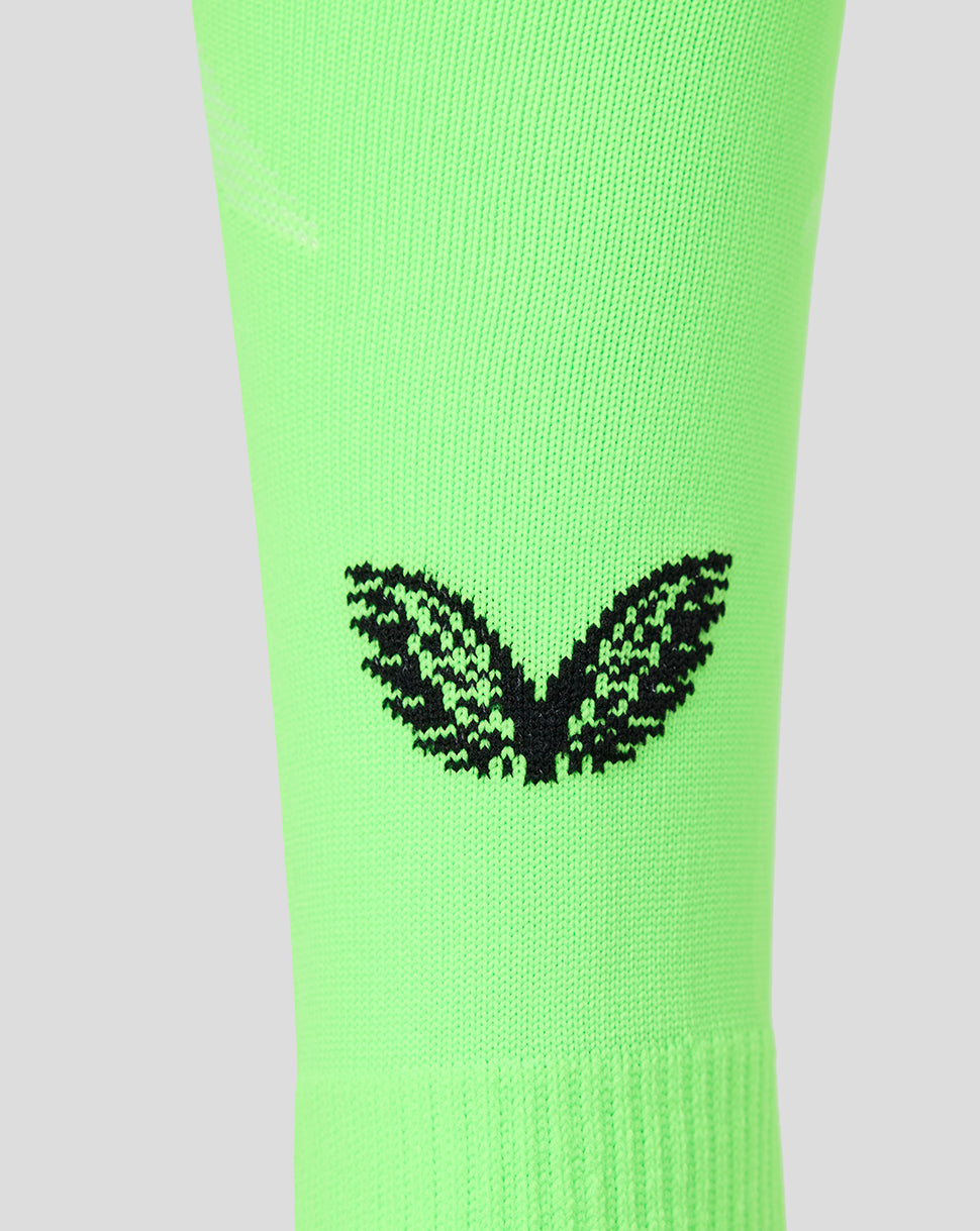 A close-up of a bright neon green athletic sock featuring a black knit butterfly logo on the calf, set against a solid light gray background.