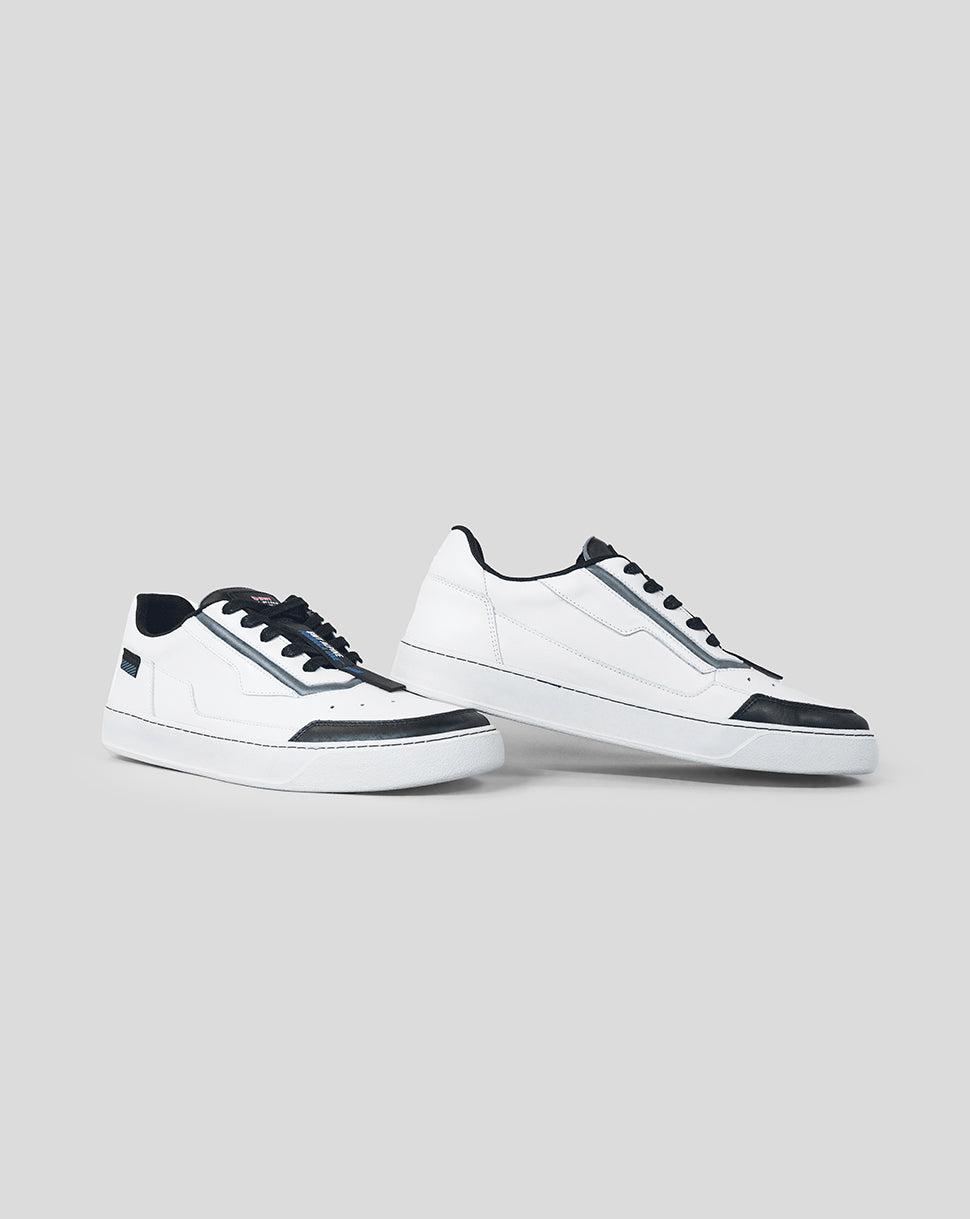 Two white Alpine Endstate sneakers with black toe caps and black laces, displayed in front and side view against a gray background.