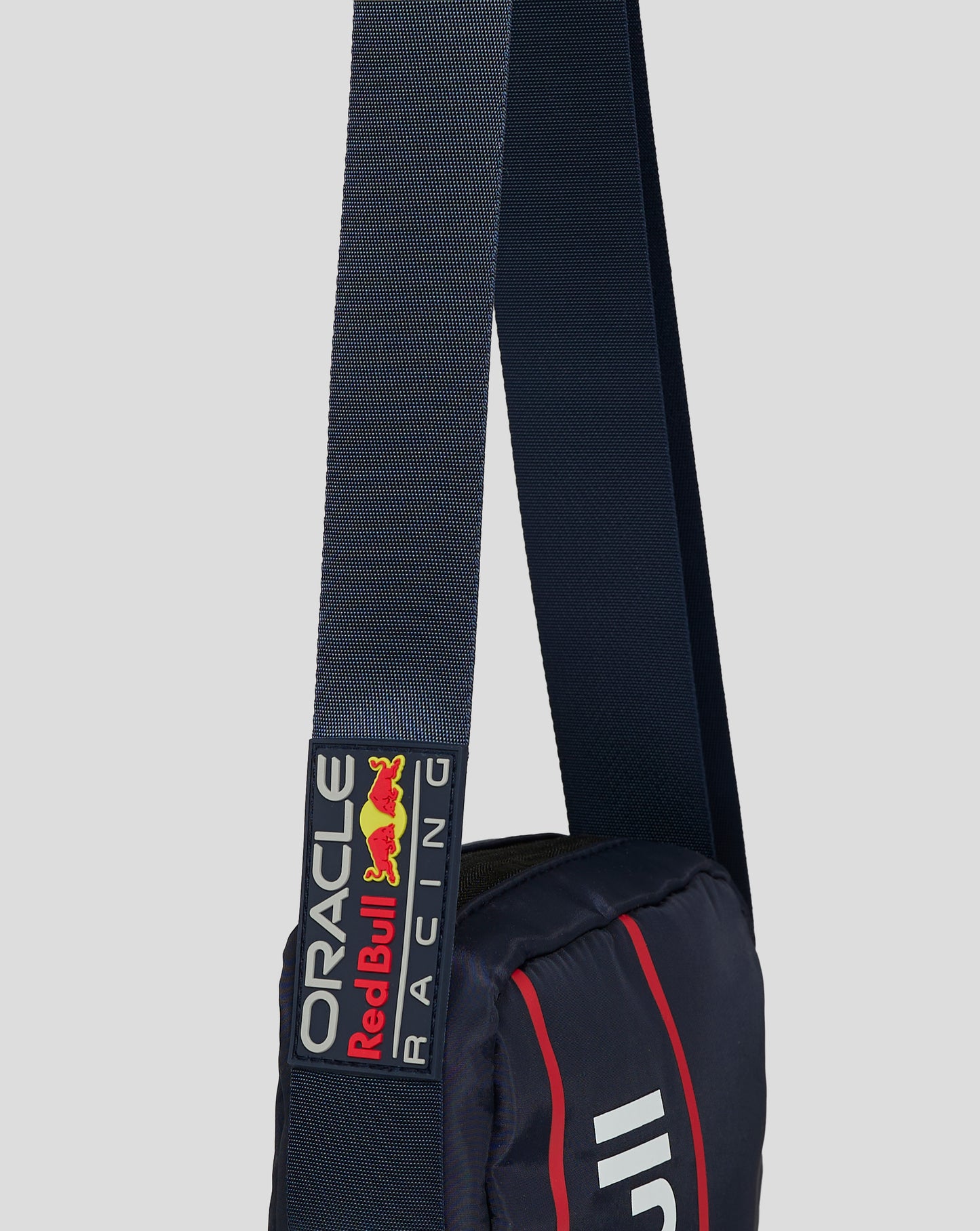 Close up of navy textured crossbody strap with Red Bull Racing logo patch and buckle