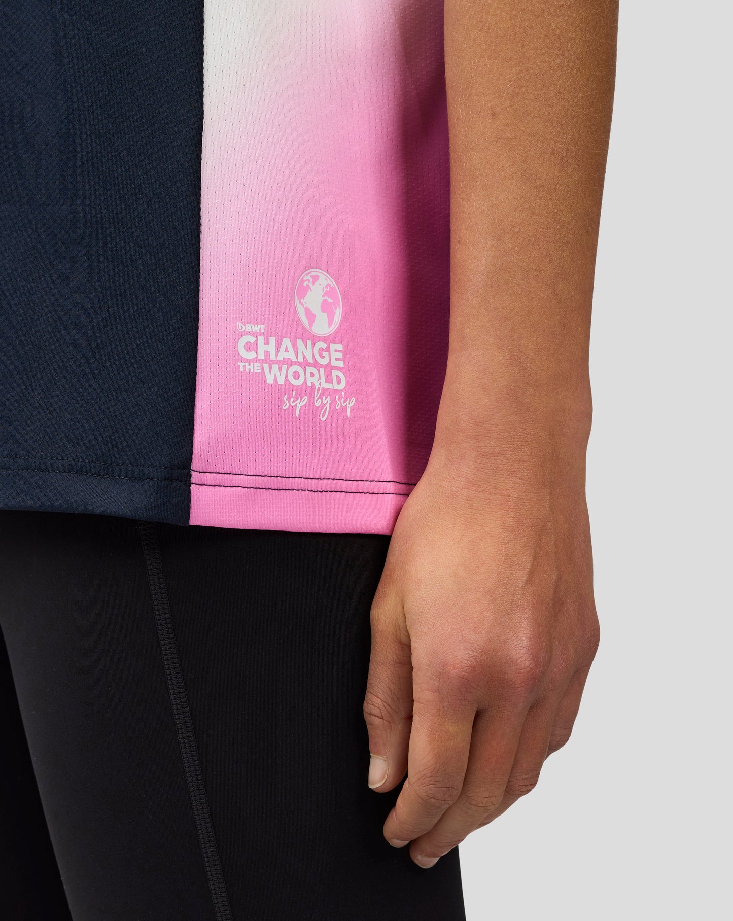 Close up of pink gradient panel on the side of a navy BWT Alpine polo with Change the World graphic