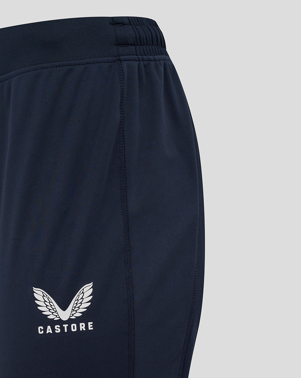 Close-up of navy drill pants leg with Castore logo and wing emblem.