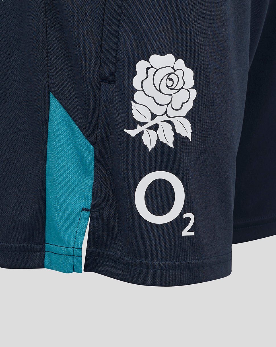 Close-up of navy shorts showing a white rose crest near the right thigh, O2 logo, and turquoise side panel