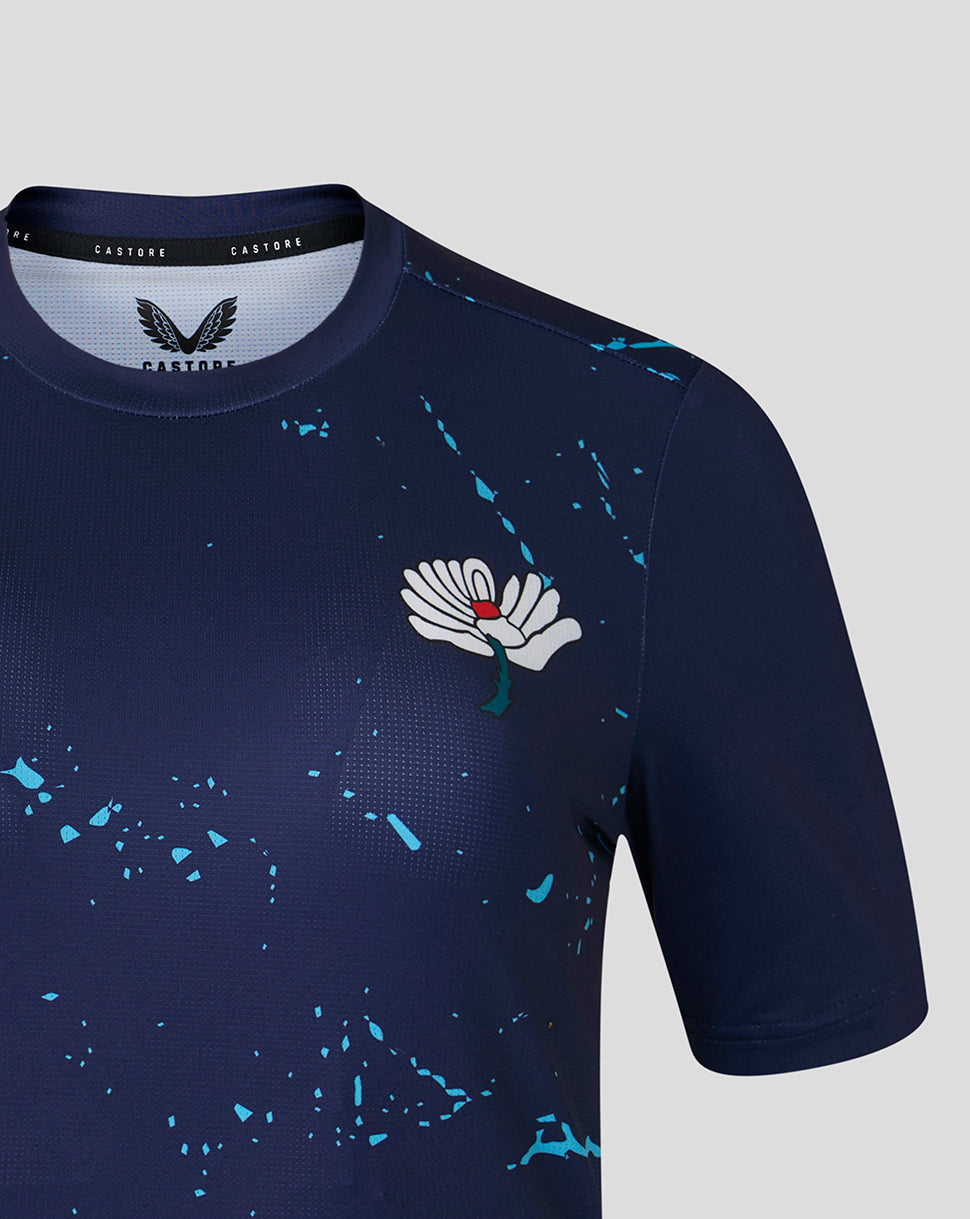 Close-up of navy Yorkshire Cricket Women's 26/27 short sleeve performance T shirt featuring White Rose crest and blue splatter pattern