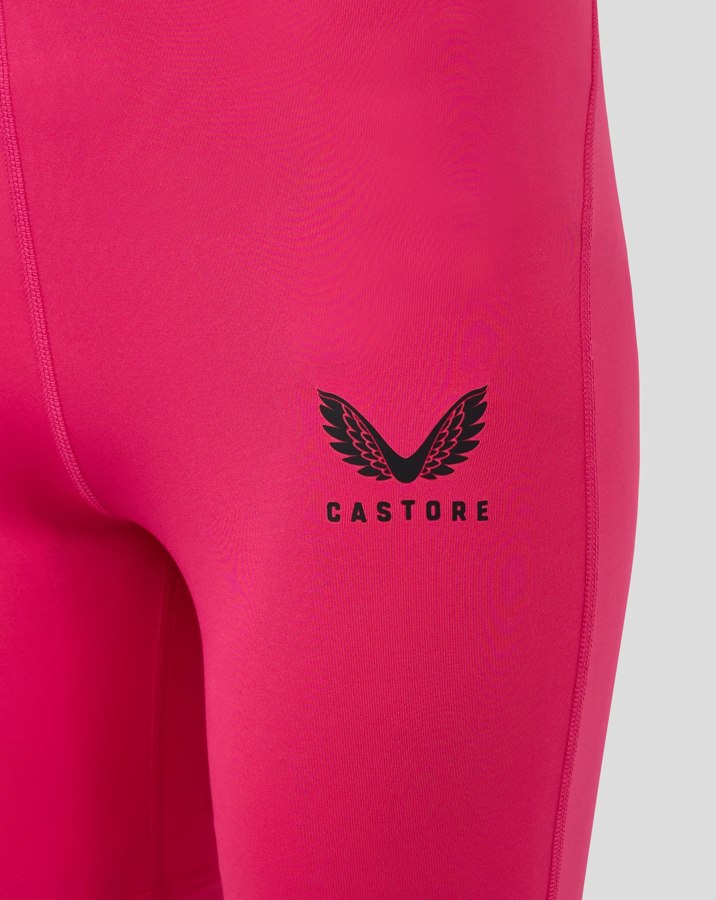 Close-up of Beetroot Purple baselayer fabric with a black winged Castore logo on the leg panel.