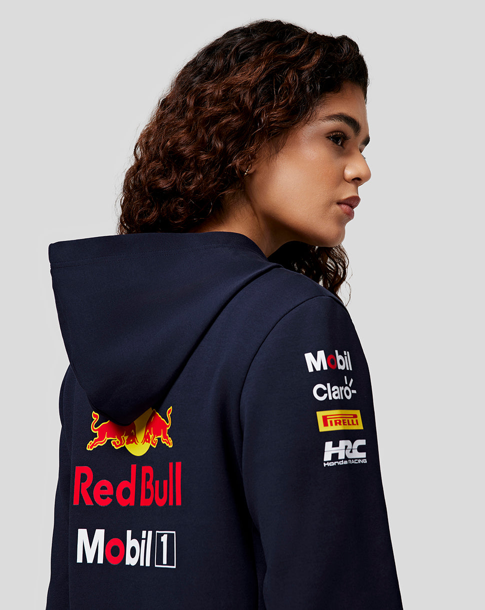 Side view of a woman in a navy Red Bull Racing hoodie showing back logo and branding on the chest and sleeve.