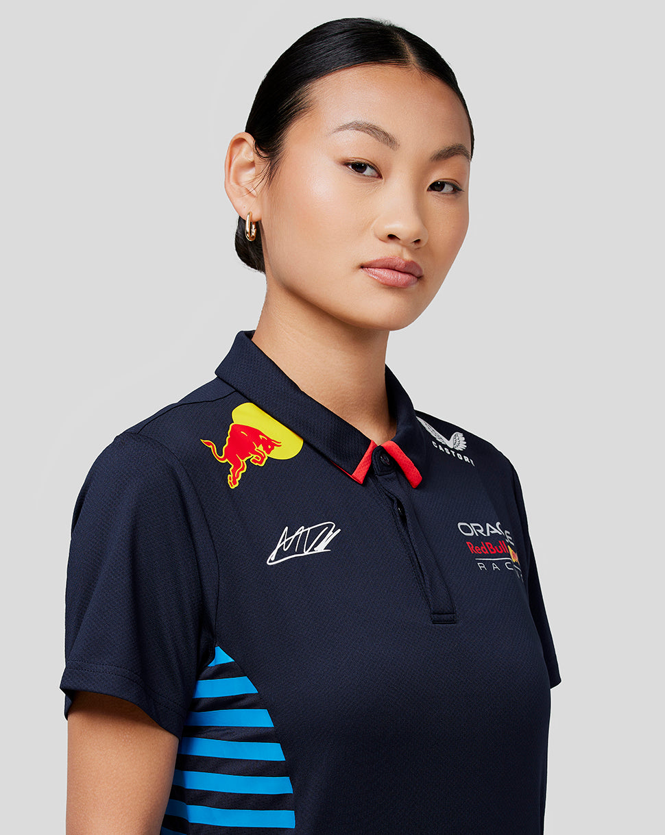Three-quarter view of a woman in a navy Oracle Red Bull Racing Women Teamline polo showing chest logos and blue side stripes