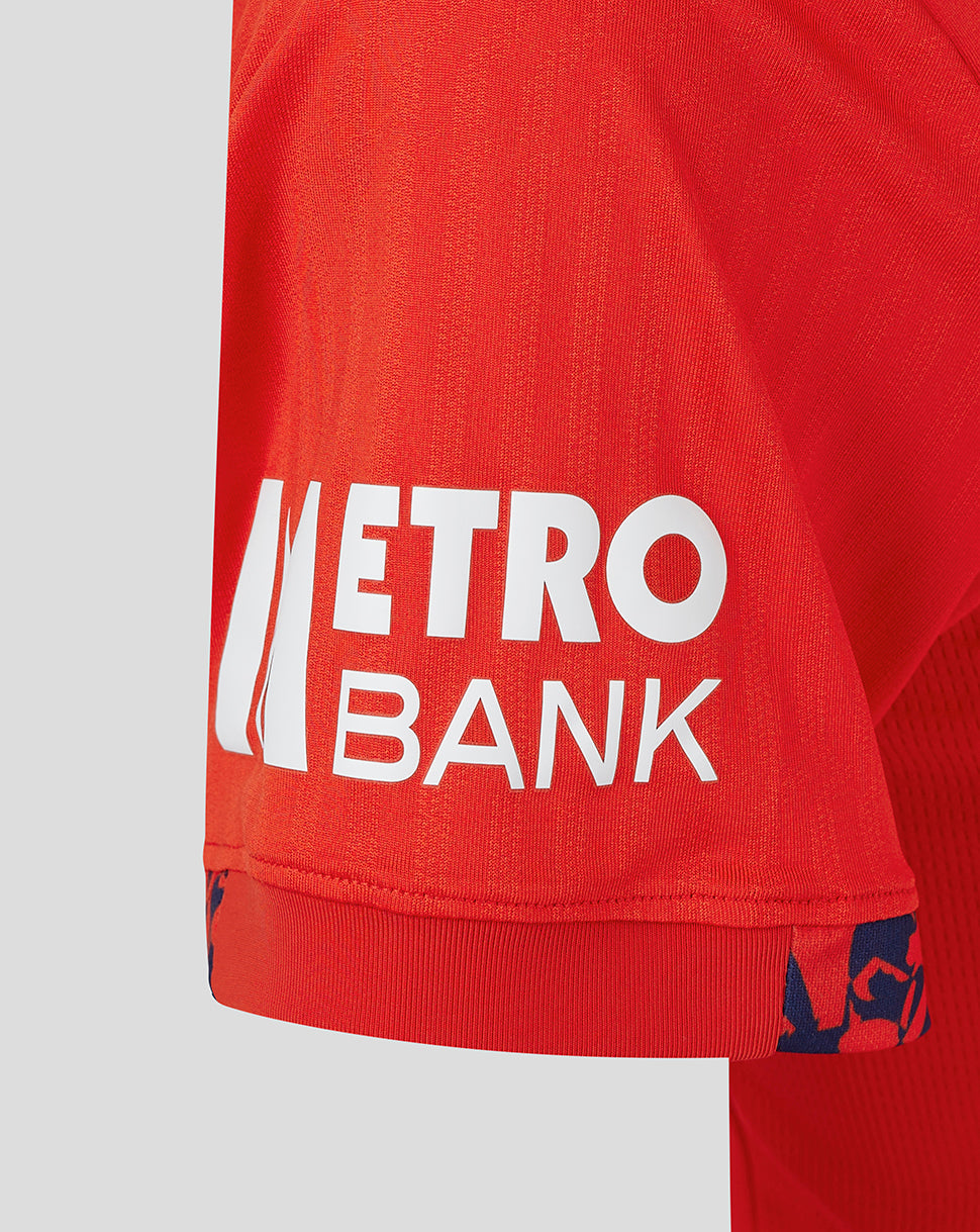 Close-up of red England women's 24/25 T20 shirt fabric with Metro Bank sponsor on the hem