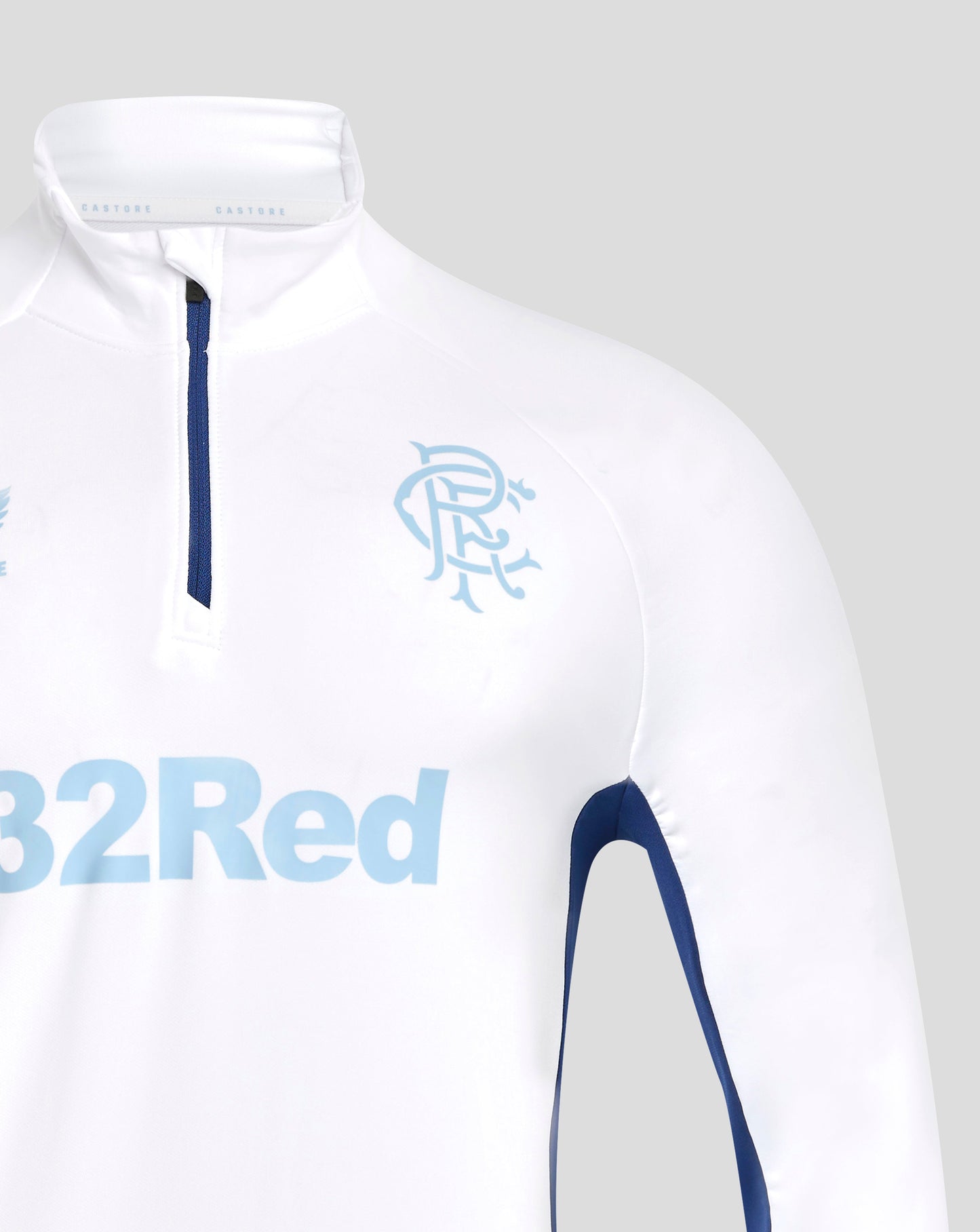 Collar close up of white training top with blue zipper and light blue crest on chest and Castore branding inside collar