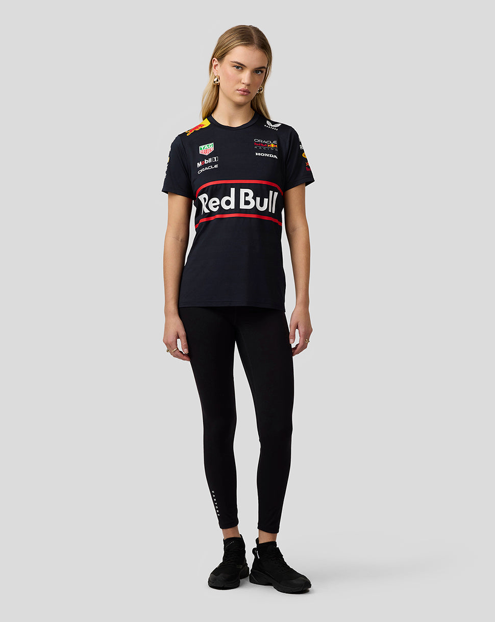 Full body front view of a woman in a navy Red Bull Racing Set Up T Shirt with large chest logo, black leggings and sneakers.