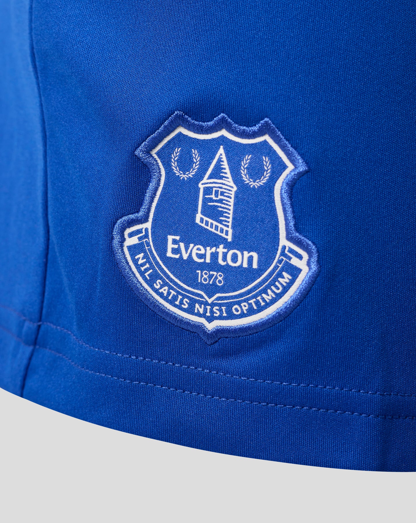 Close-up of blue fabric with an Everton crest patch on junior home shorts