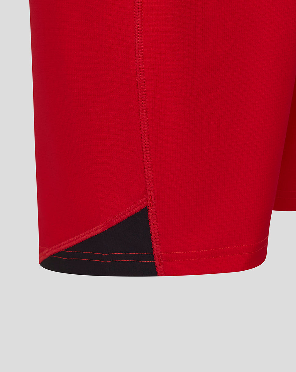 Close up of red shorts hem showing a black underlayer panel and visible stitching
