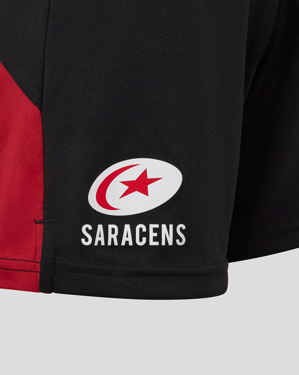 Close-up of Saracens logo on the lower left side of black shorts with a red panel