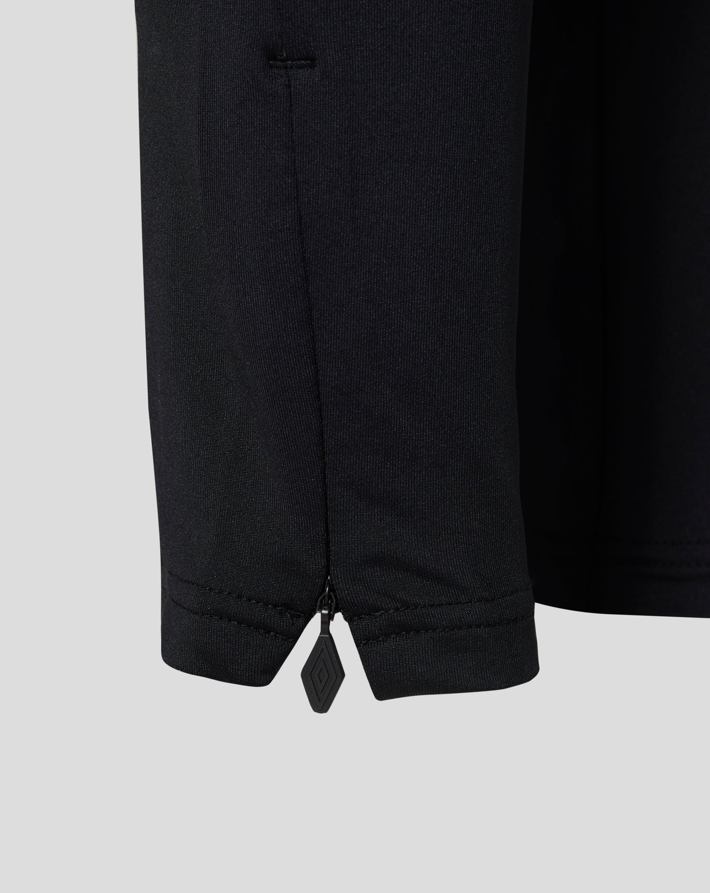 Close-up of dark knit fabric with ankle zipper on West Ham Junior Pro Training Knit Pants