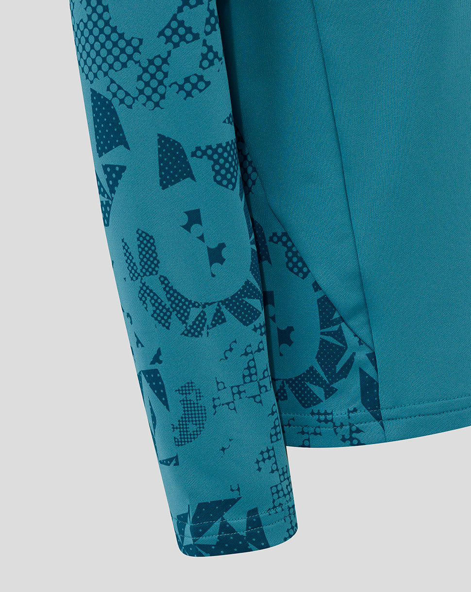 Sleeve close-up showing abstract geometric print on storm blue junior England performance midlayer.