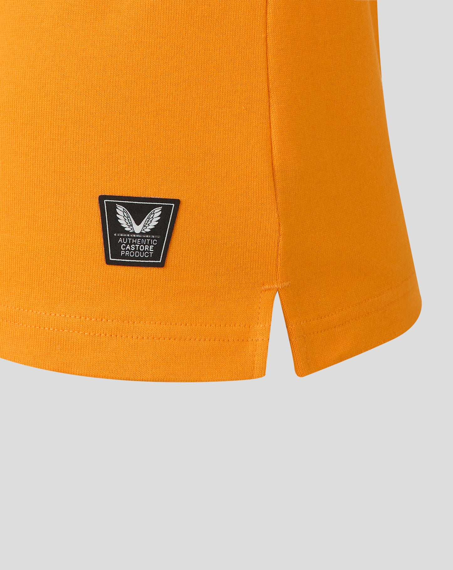 Close view of shield patch on orange jersey with authentic Castore product label.