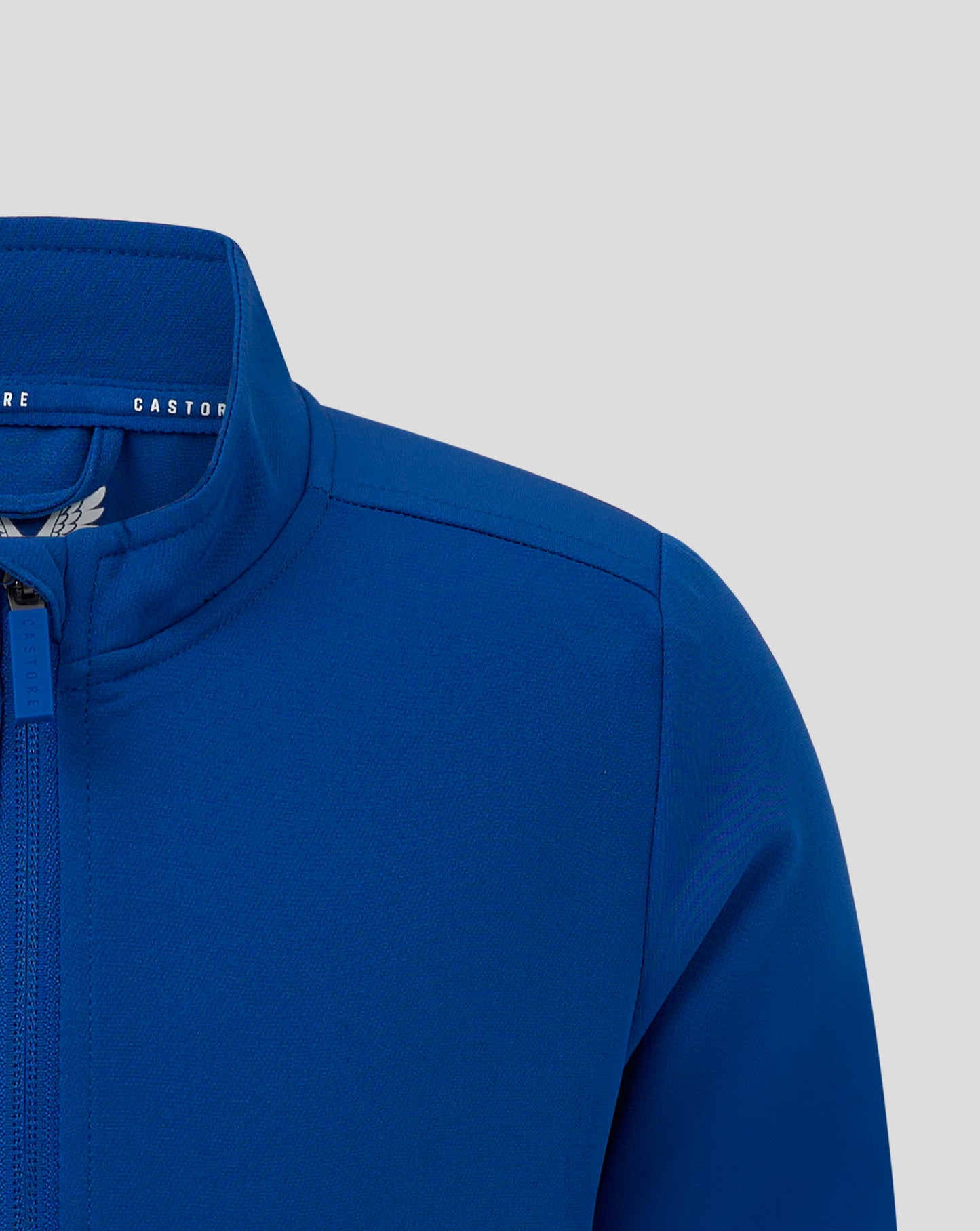 Partial front view of blue track jacket with zipper Castore branding and wing emblem