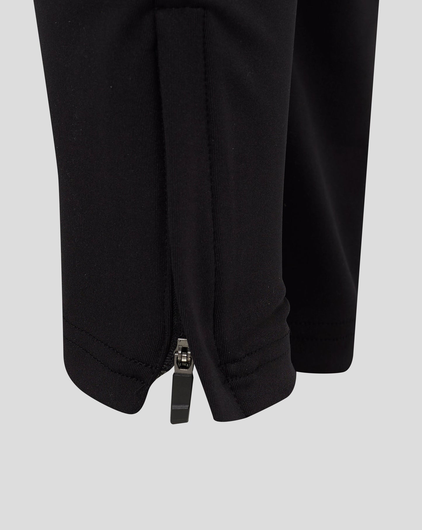 Close up of black pant leg with a visible zipper at the ankle and clean seam