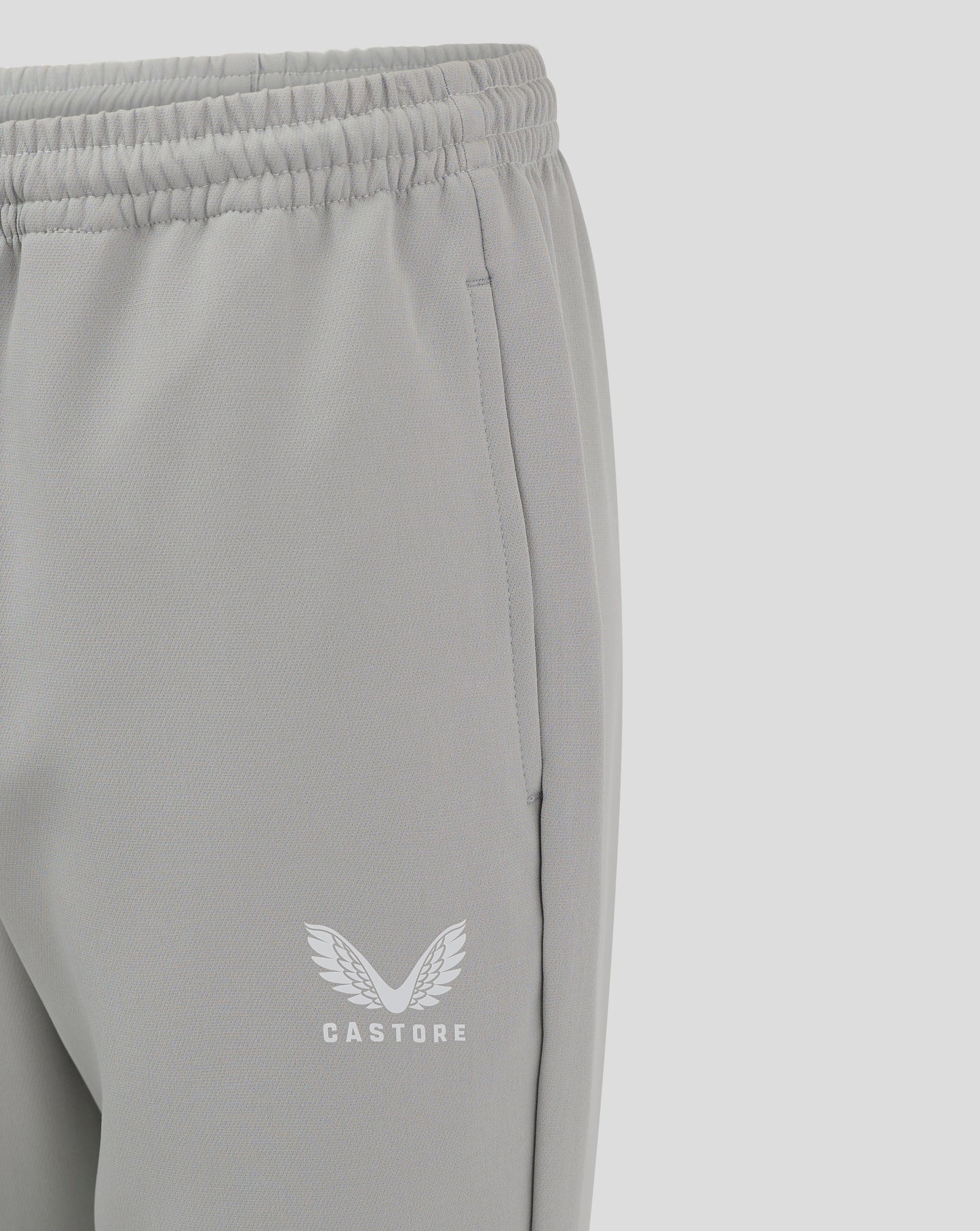 Close-up of grey track pants showing elastic waistband and Castore logo near the hem