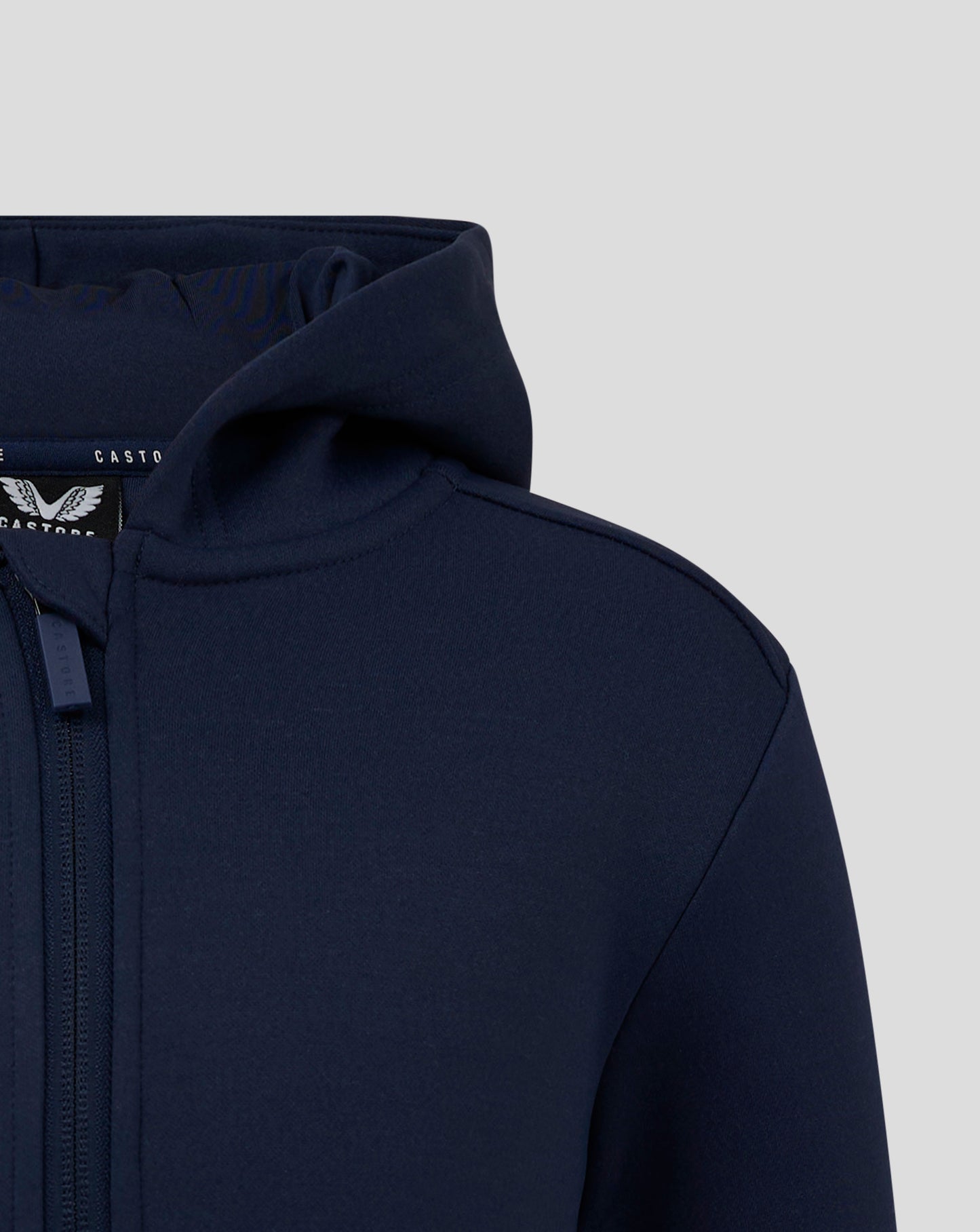 Close up of navy Junior Full Zip Brushback Hoodie showing hood edge and zipper with Castore logo