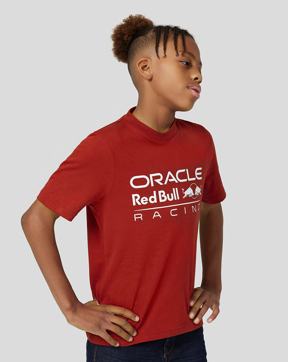 Side profile of a young person wearing a red Oracle Red Bull Racing juniors T shirt with a white chest logo