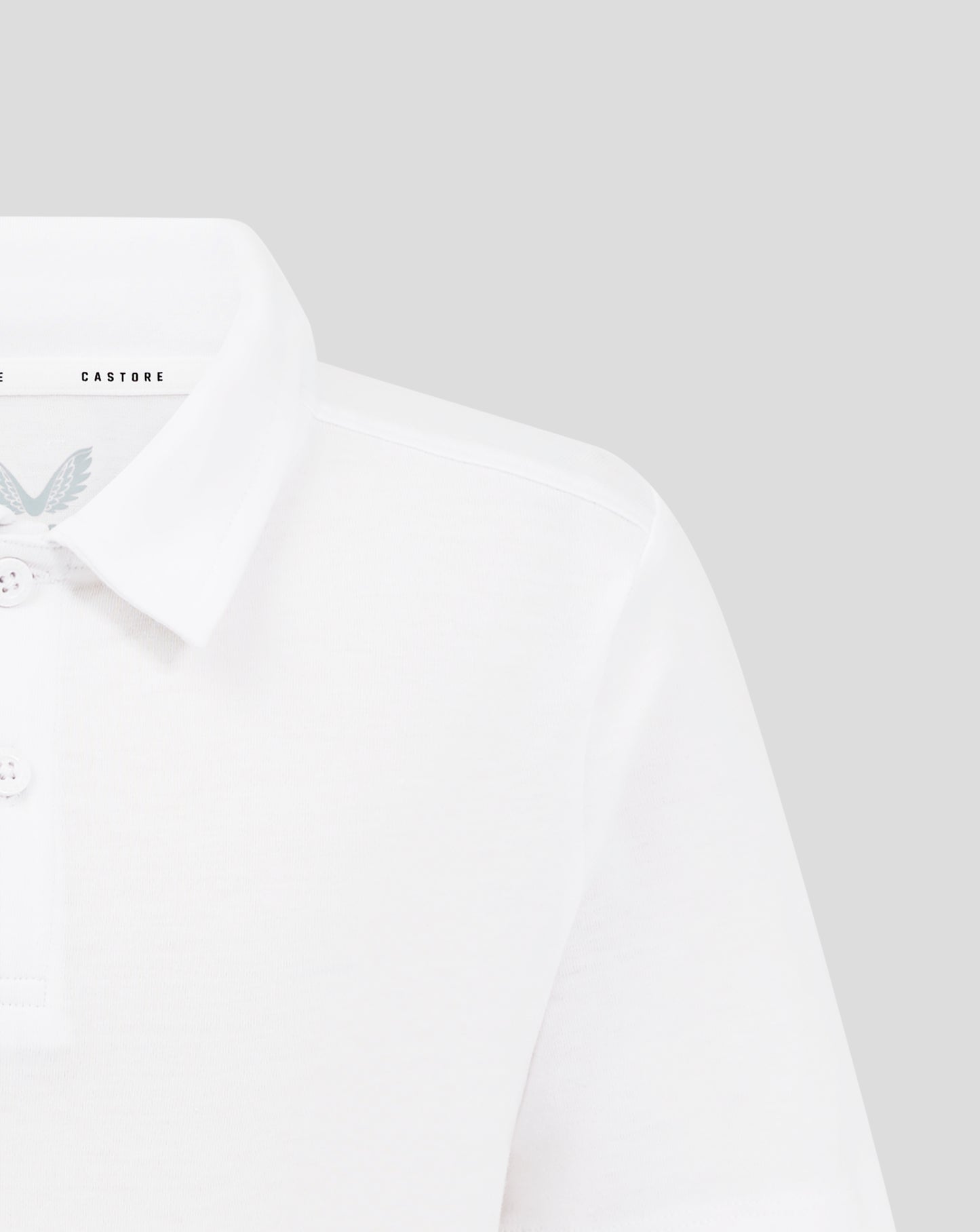 Close up of a white Junior Cotton Leisure Polo showing a collar three button placket and Castore logo on the inner collar