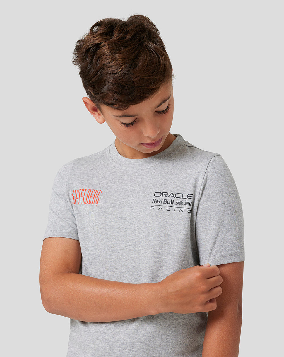 Front view of a child in a grey marl Spielberg T shirt showing the red Spielberg logo on the chest and the Oracle Red Bull Racing logo on the front